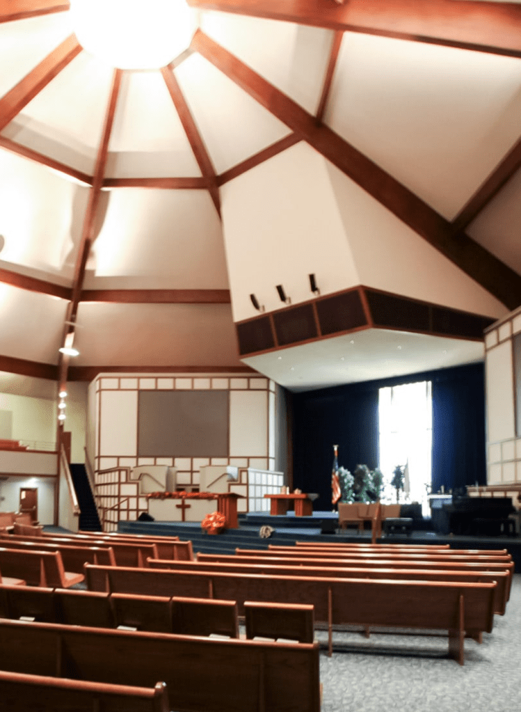 Interior of a large church with a high ceiling and multiple rows of pews for attendees.