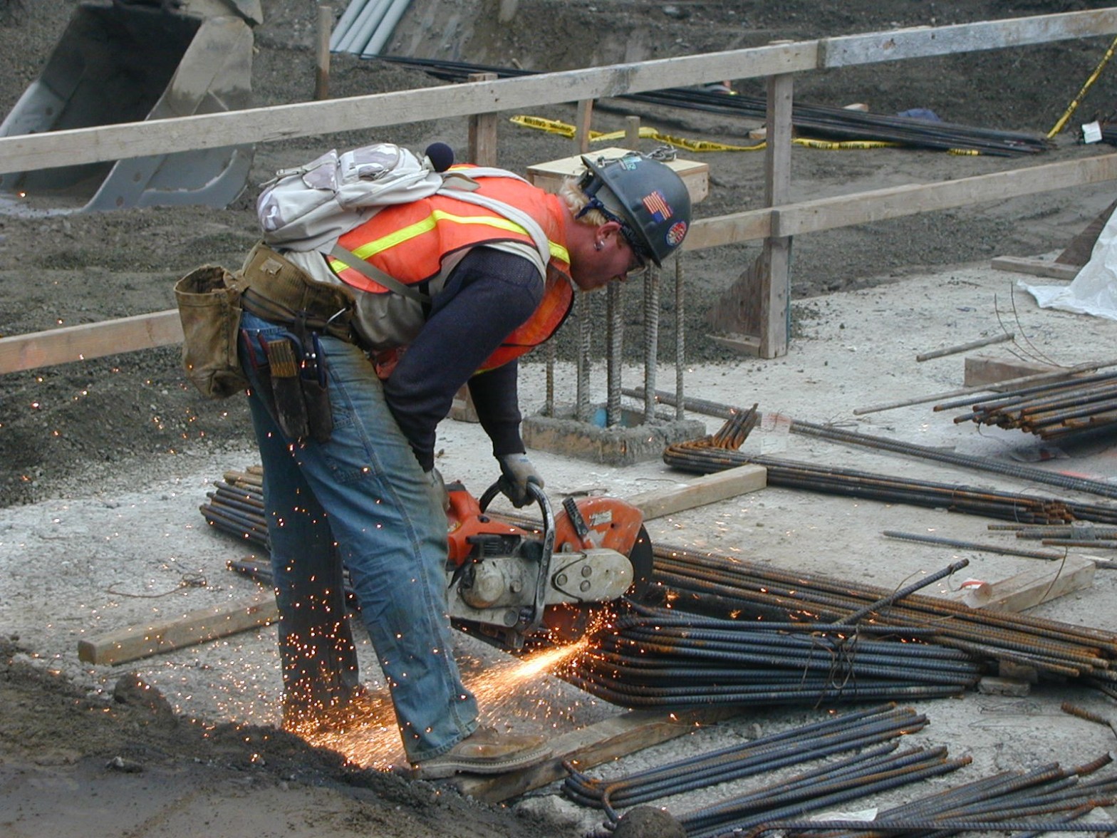 A construction worker cuts rebar with a cut-off saw.
