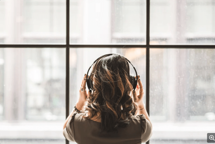 Woman listening to headphones while looking out window