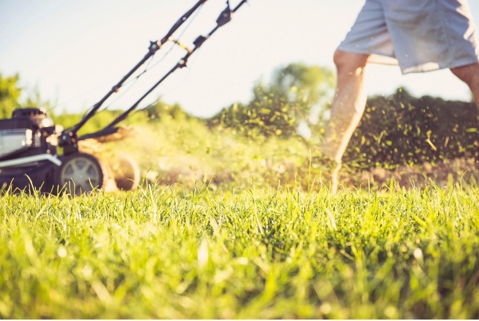 Person mowing lawn with a gas-powered mower