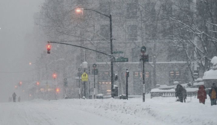 Pedestrians walk in a snowy city.