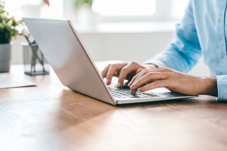 Photo of a person's hands typing on a laptop