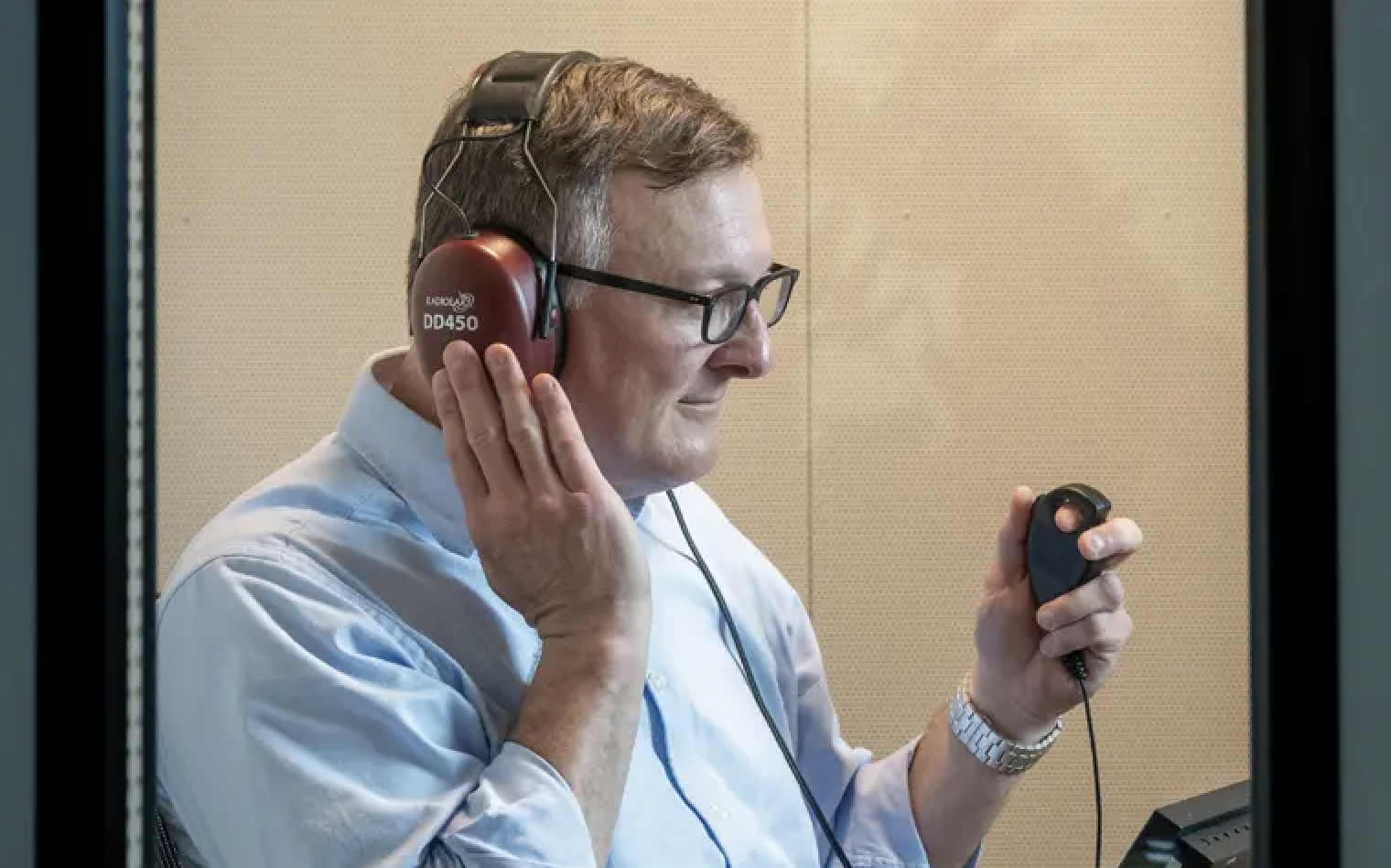 Professor Rick Neitzel wears headphones as he takes a hearing test in an audio booth.